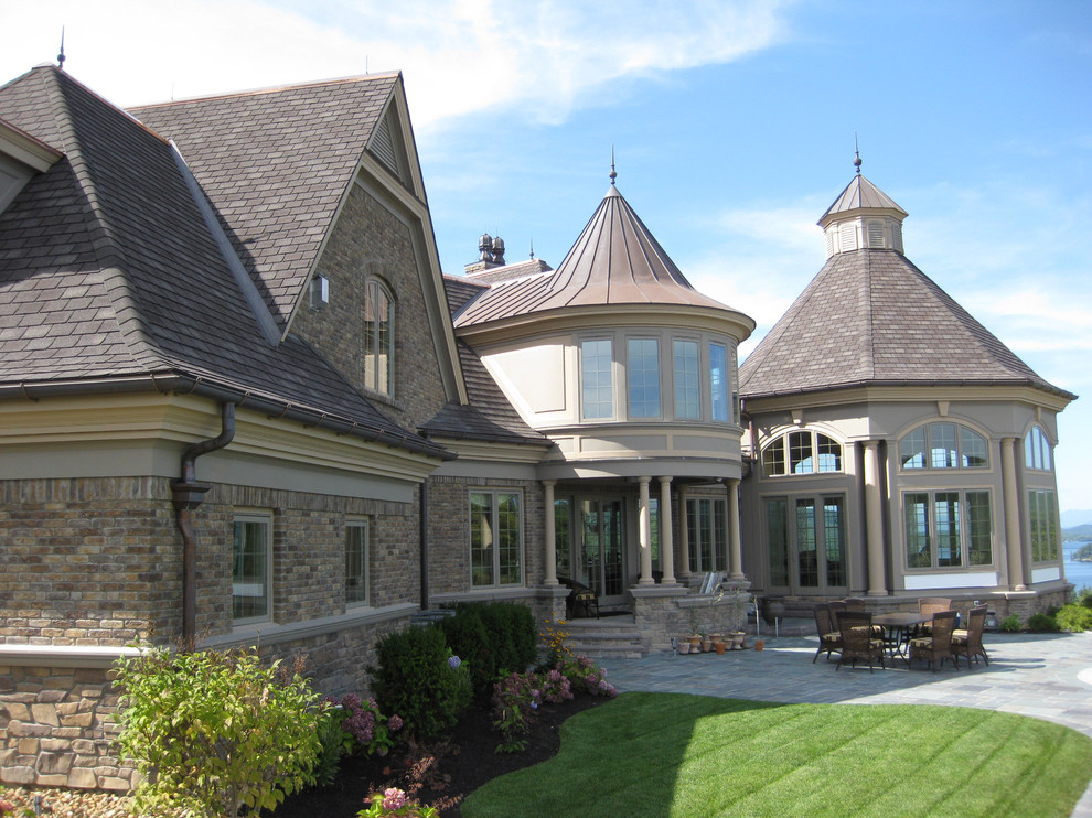 Réalisation d'une très grande façade de maison marron craftsman en pierre à deux étages et plus avec un toit à deux pans et un toit en tuile.