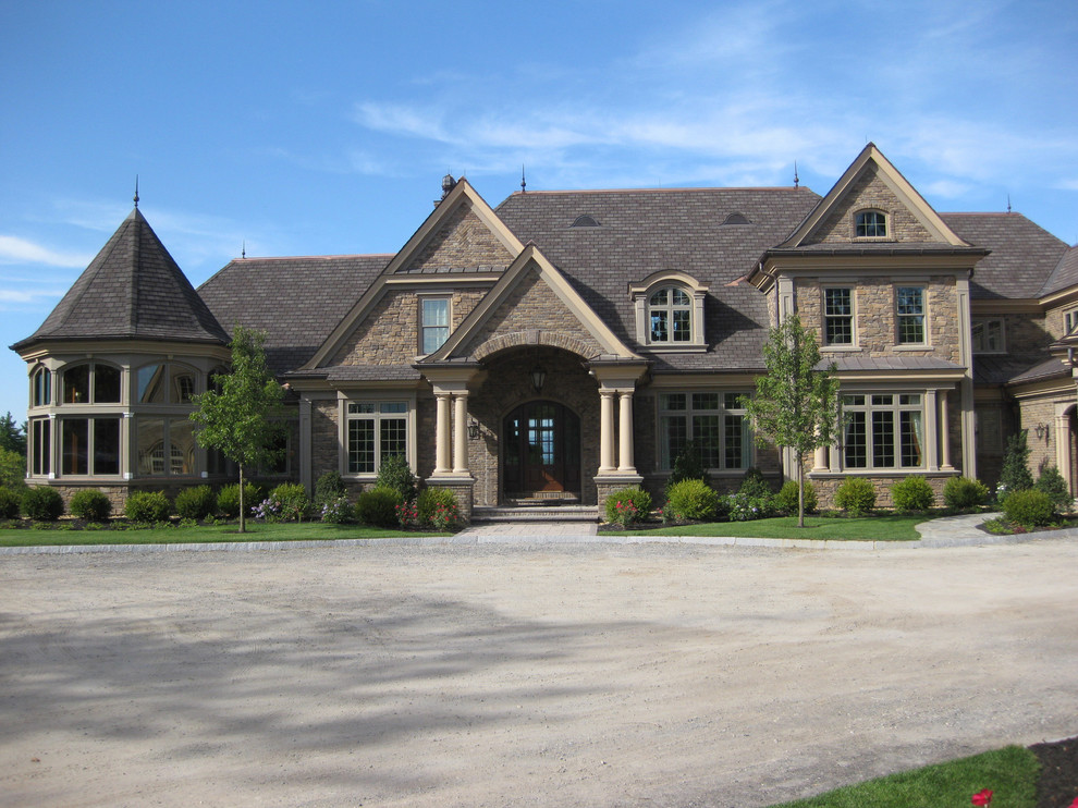 Esempio della villa ampia marrone american style a tre piani con rivestimento in pietra, tetto a capanna e copertura in tegole