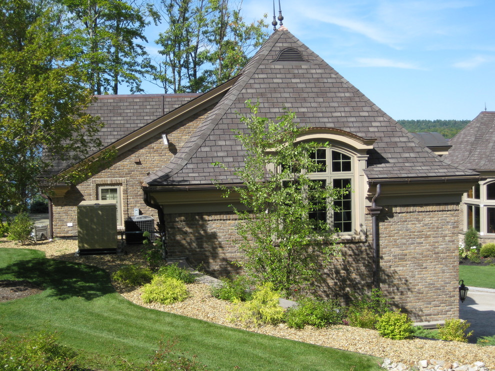 Idee per la villa ampia marrone american style a tre piani con rivestimento in pietra, tetto a capanna e copertura in tegole