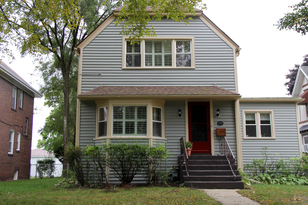 This is an example of a medium sized and blue classic two floor detached house in Chicago with vinyl cladding and a shingle roof.