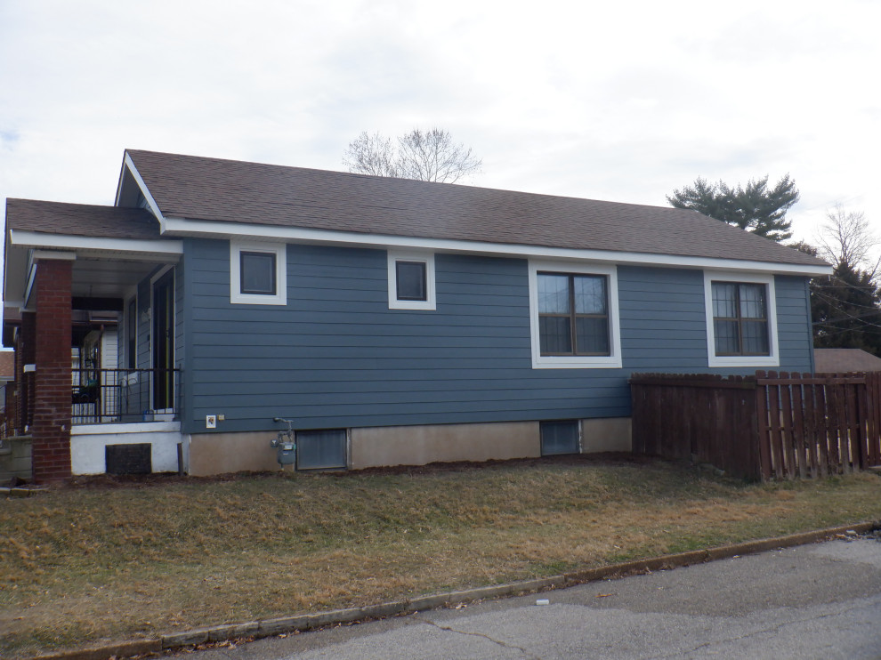 Foto på ett litet amerikanskt blått hus, med allt i ett plan, fiberplattor i betong, sadeltak och tak i shingel