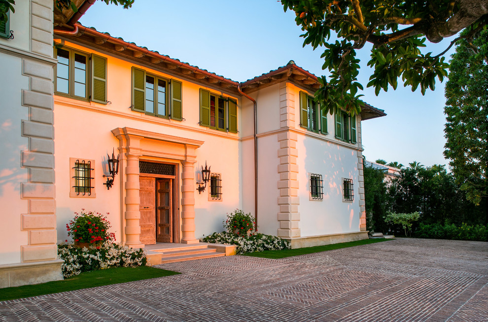 Diseño de fachada de casa blanca mediterránea extra grande de dos plantas con revestimiento de estuco, tejado a cuatro aguas y tejado de teja de barro