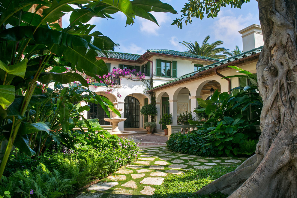 Imagen de fachada de casa blanca mediterránea extra grande de dos plantas con revestimiento de estuco, tejado a cuatro aguas y tejado de teja de barro