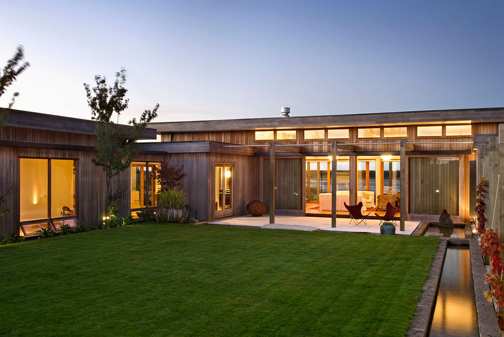 This is an example of a contemporary bungalow house exterior in Wellington with wood cladding and a flat roof.