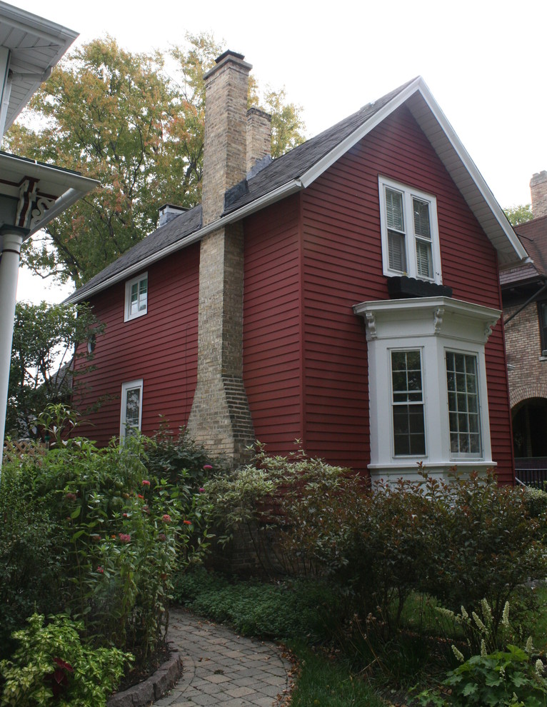 Immagine della facciata di una casa rossa country a due piani di medie dimensioni con tetto a capanna e rivestimento con lastre in cemento