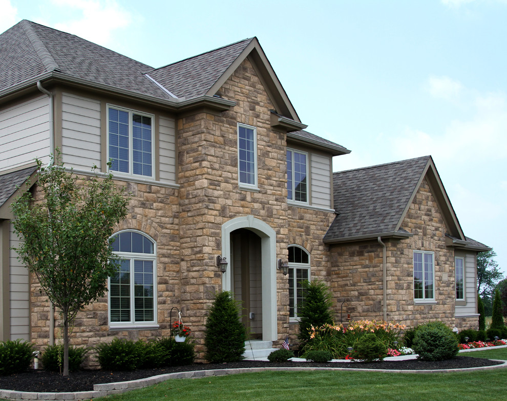 Cette image montre une grande façade de maison marron craftsman en pierre à deux étages et plus avec un toit à deux pans et un toit en tuile.