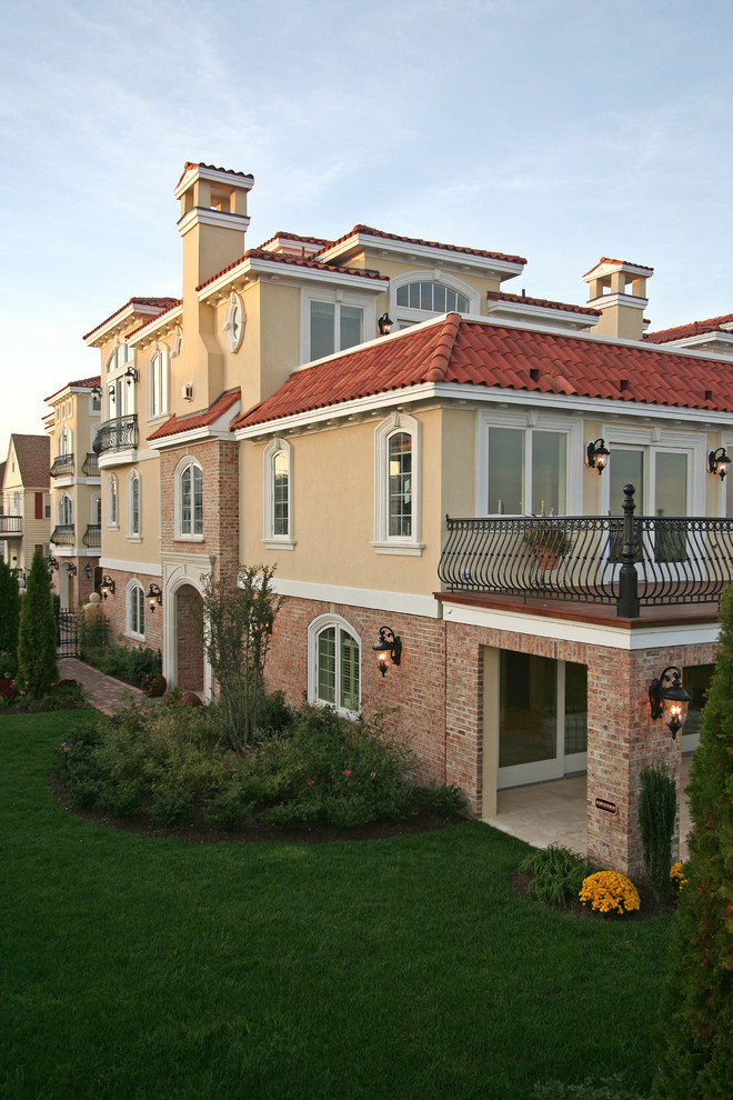 Источник вдохновения для домашнего уюта: большой, трехэтажный, кирпичный, желтый дом в средиземноморском стиле