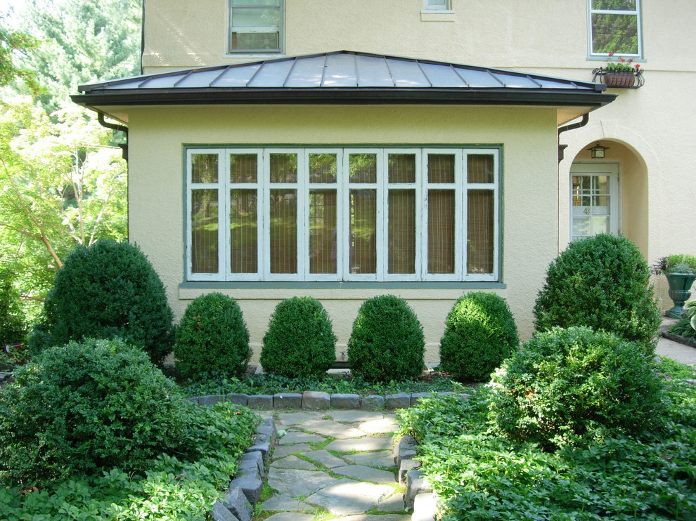 Diseño de fachada de casa amarilla tradicional de tamaño medio de dos plantas con revestimiento de estuco, tejado a cuatro aguas y tejado de varios materiales