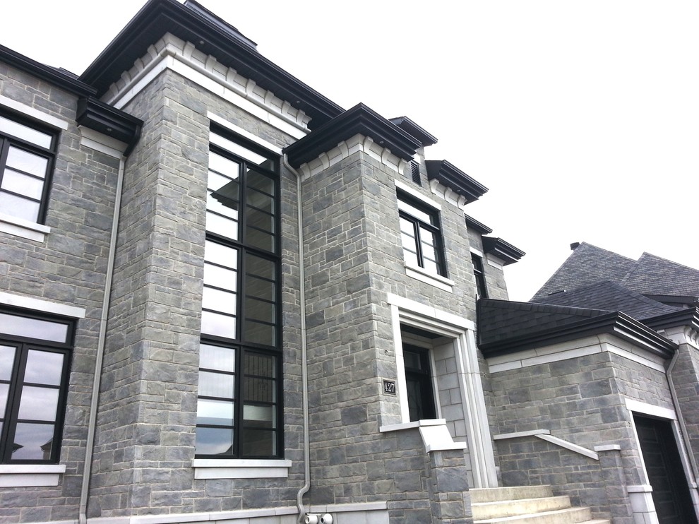 Пример оригинального дизайна: большой, двухэтажный, серый дом в стиле неоклассика (современная классика) с облицовкой из камня