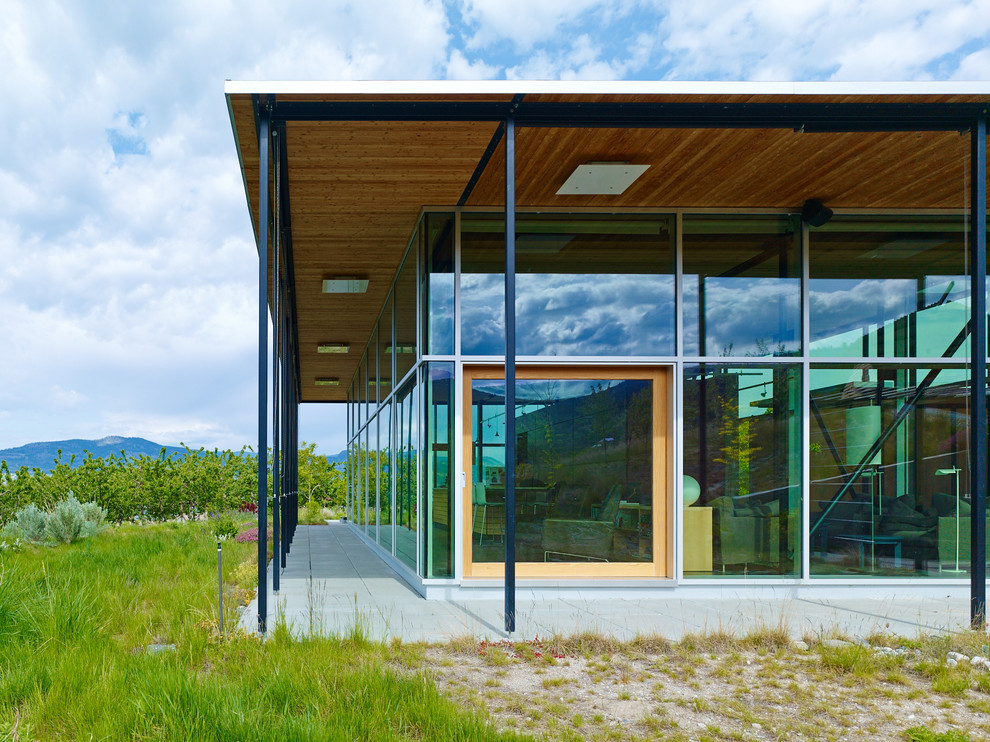 Imagen de fachada moderna grande de una planta con revestimiento de vidrio y tejado plano