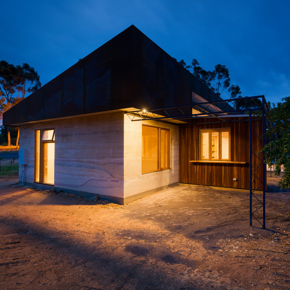 Foto på ett mellanstort funkis beige hus, med allt i ett plan, stuckatur, platt tak och tak i metall