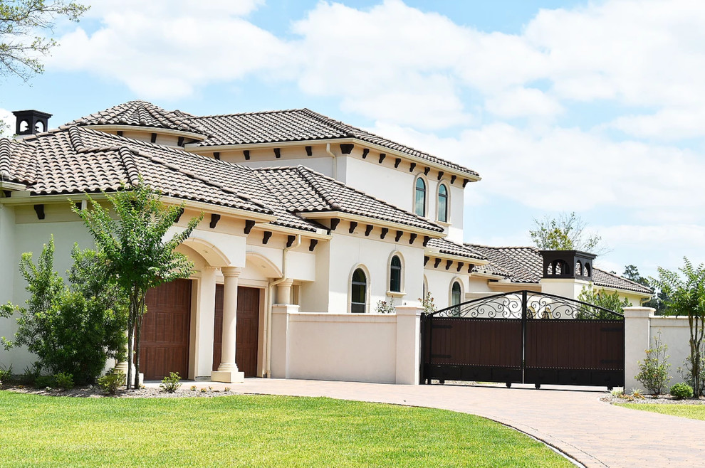This is an example of a medium sized and beige mediterranean two floor detached house in Houston with stone cladding, a hip roof and a tiled roof.