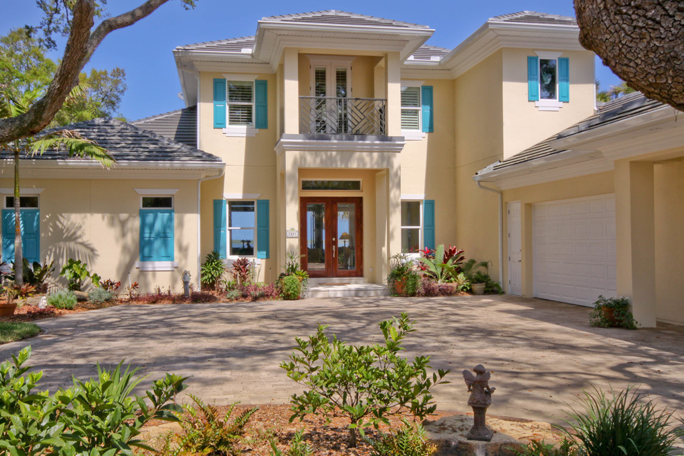 Inspiration for a tropical beige two-story stucco house exterior remodel in Orlando