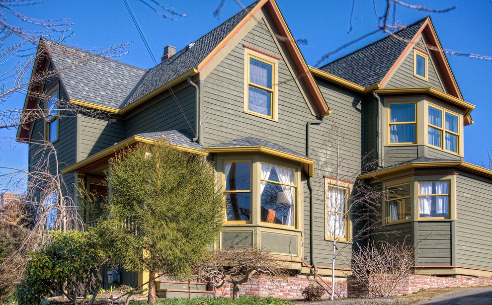 Esempio della facciata di una casa grande verde country a due piani con rivestimento in legno
