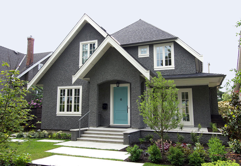 Example of a mid-sized classic gray two-story stucco exterior home design in Vancouver with a shingle roof