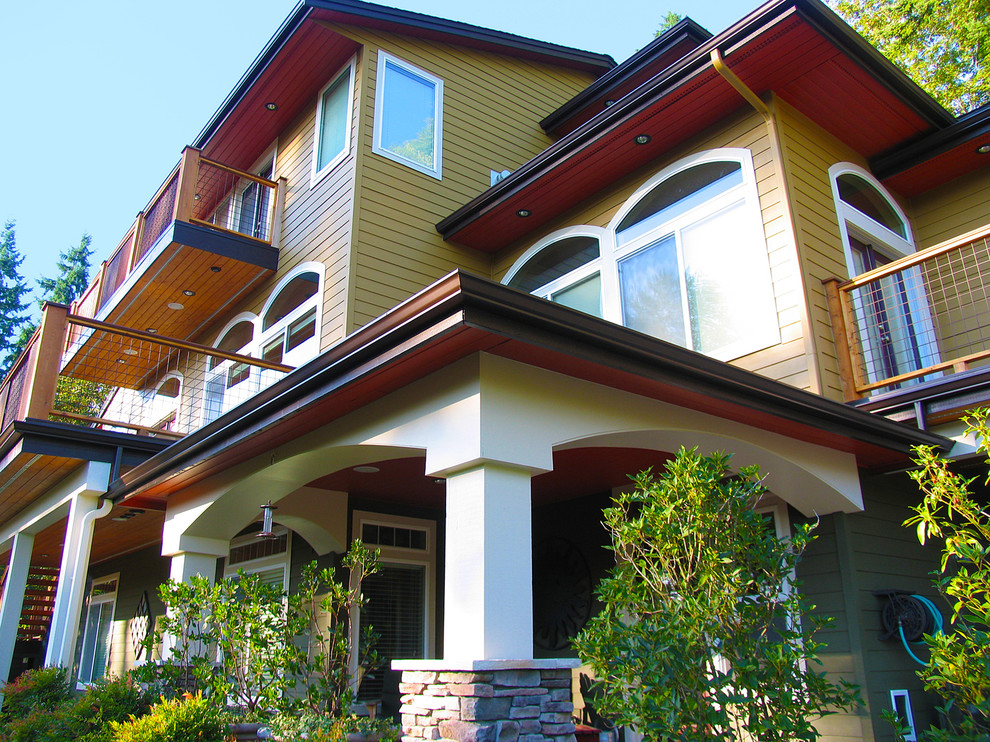Foto della facciata di una casa grande marrone american style a tre piani con rivestimento in legno e tetto a capanna