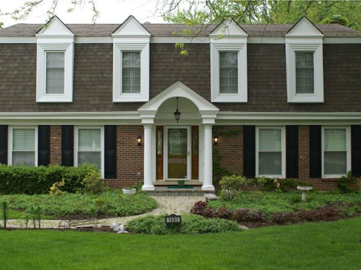 На фото: двухэтажный, коричневый дом в классическом стиле с комбинированной облицовкой с