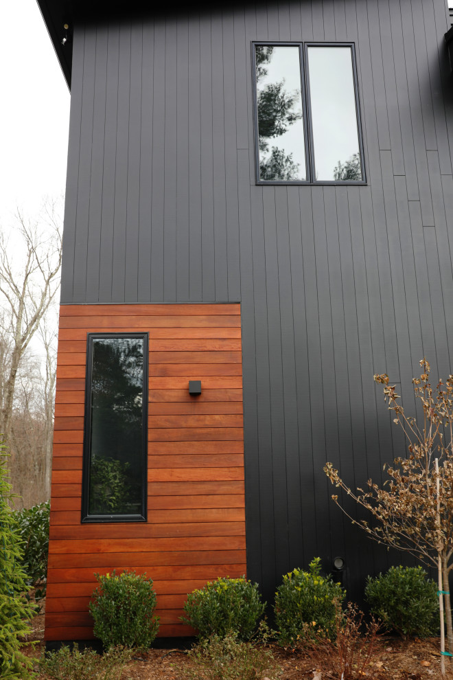 Aménagement d'une façade de maison noire contemporaine de taille moyenne et à un étage avec un revêtement mixte, un toit en appentis et un toit en métal.
