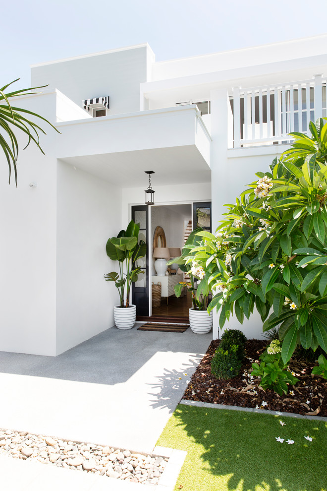 Exemple d'une grande façade de maison blanche bord de mer en panneau de béton fibré avec un toit plat et un toit en tuile.