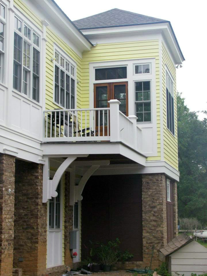 Réalisation d'une façade de maison jaune tradition en bois de taille moyenne et à un étage avec un toit à quatre pans.
