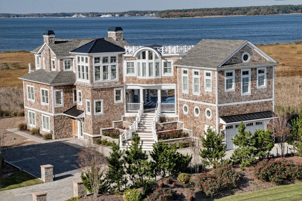 Photo of a large coastal house exterior in Other with three floors and wood cladding.