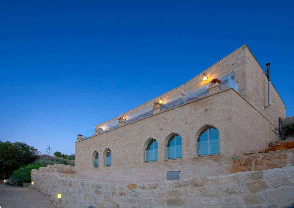 Esempio della facciata di una casa mediterranea a due piani di medie dimensioni con rivestimento in pietra