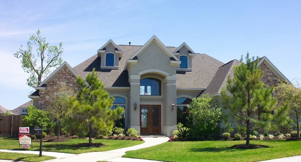 This is an example of a large and beige classic two floor render house exterior in Houston.