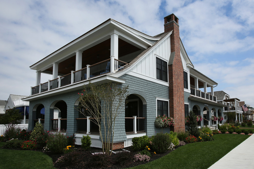 Стильный дизайн: большой, двухэтажный, деревянный, синий дом в морском стиле с двускатной крышей - последний тренд