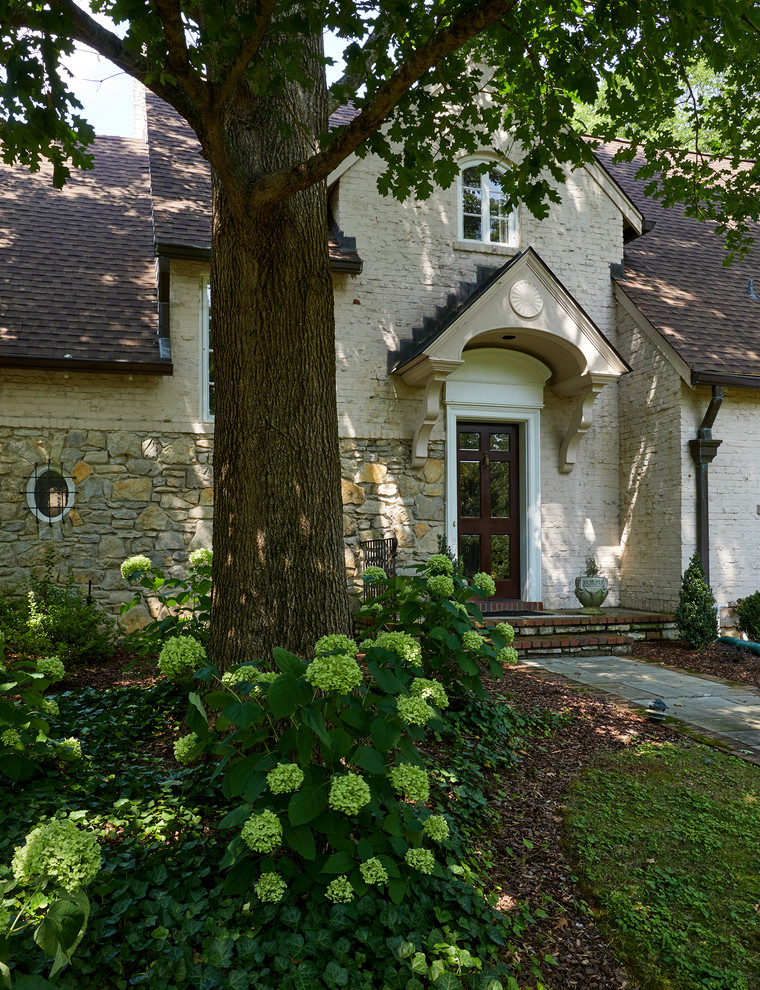 Large and beige nautical two floor brick detached house in Nashville with a shingle roof.