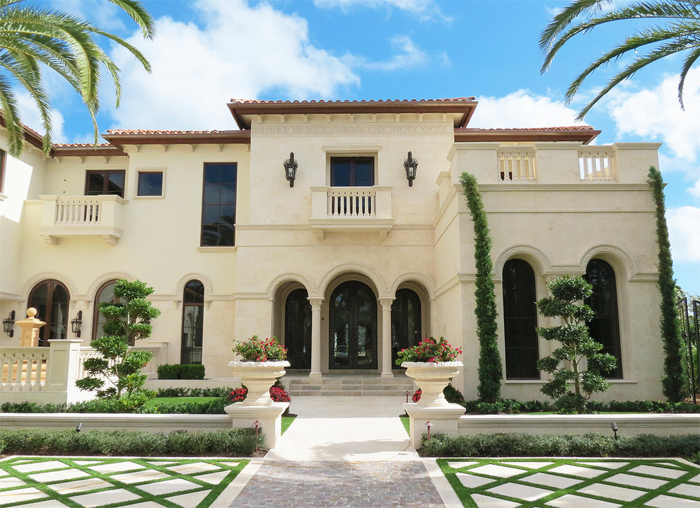 Beige and large mediterranean two floor house exterior in Miami with mixed cladding and a tiled roof.