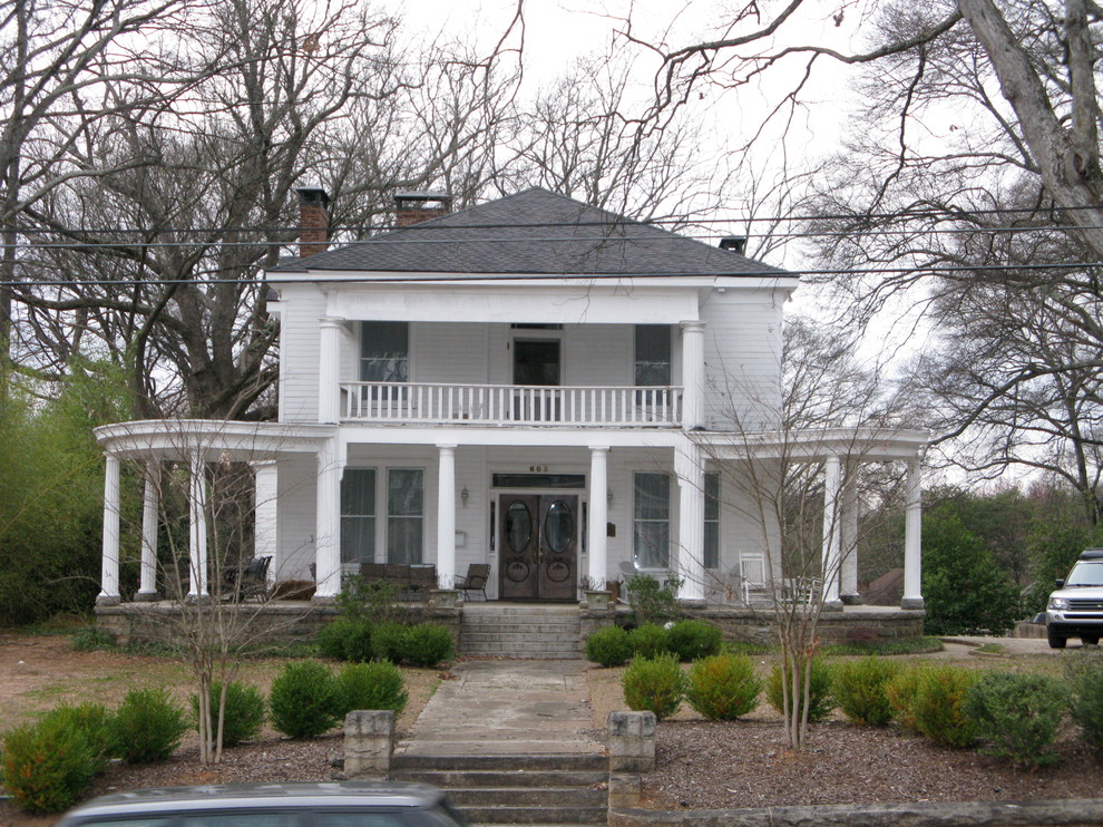 This is an example of a medium sized and white traditional two floor house exterior in Atlanta with a hip roof and wood cladding.
