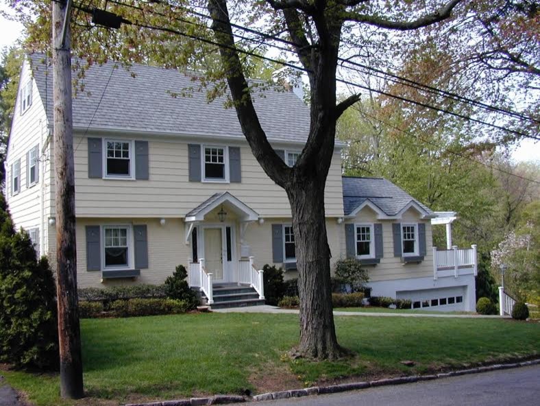 This is an example of a large and yellow traditional two floor semi-detached house in New York with wood cladding, a pitched roof and a shingle roof.