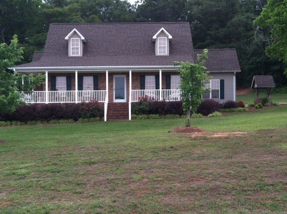 Mid-sized traditional brown two-story brick exterior home idea in Other with a clipped gable roof