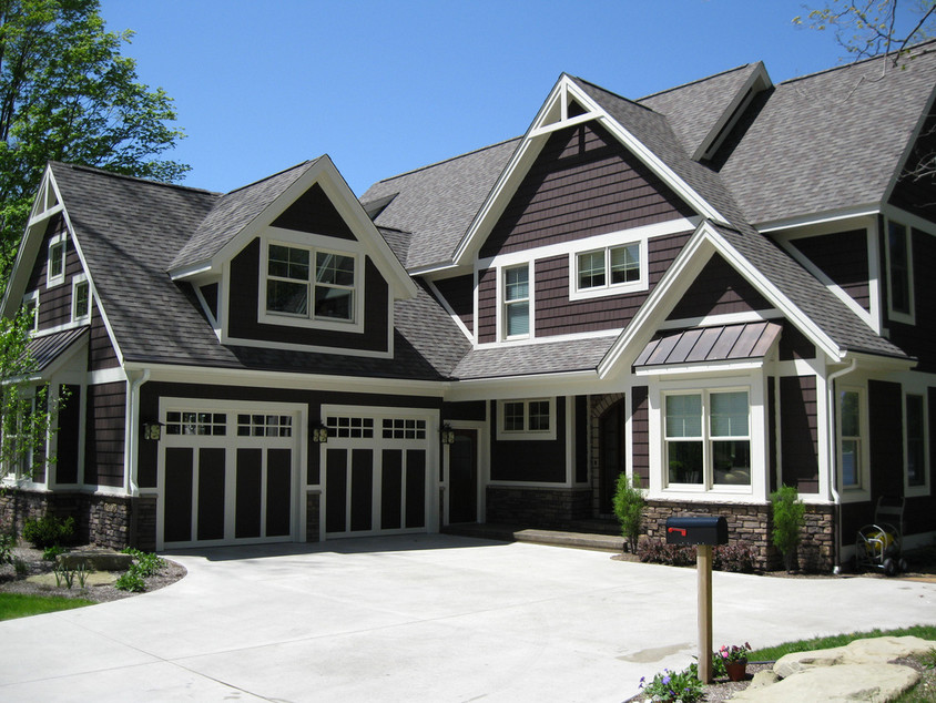 На фото: большой, трехэтажный, коричневый дом в стиле кантри с комбинированной облицовкой с