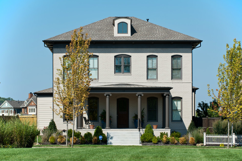 Foto della facciata di una casa grande classica a tre piani con rivestimento in mattoni e tetto a padiglione
