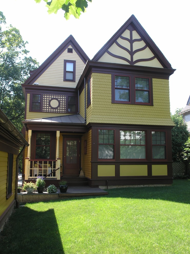 Esempio della facciata di una casa verde classica a due piani con rivestimento in legno e tetto a capanna