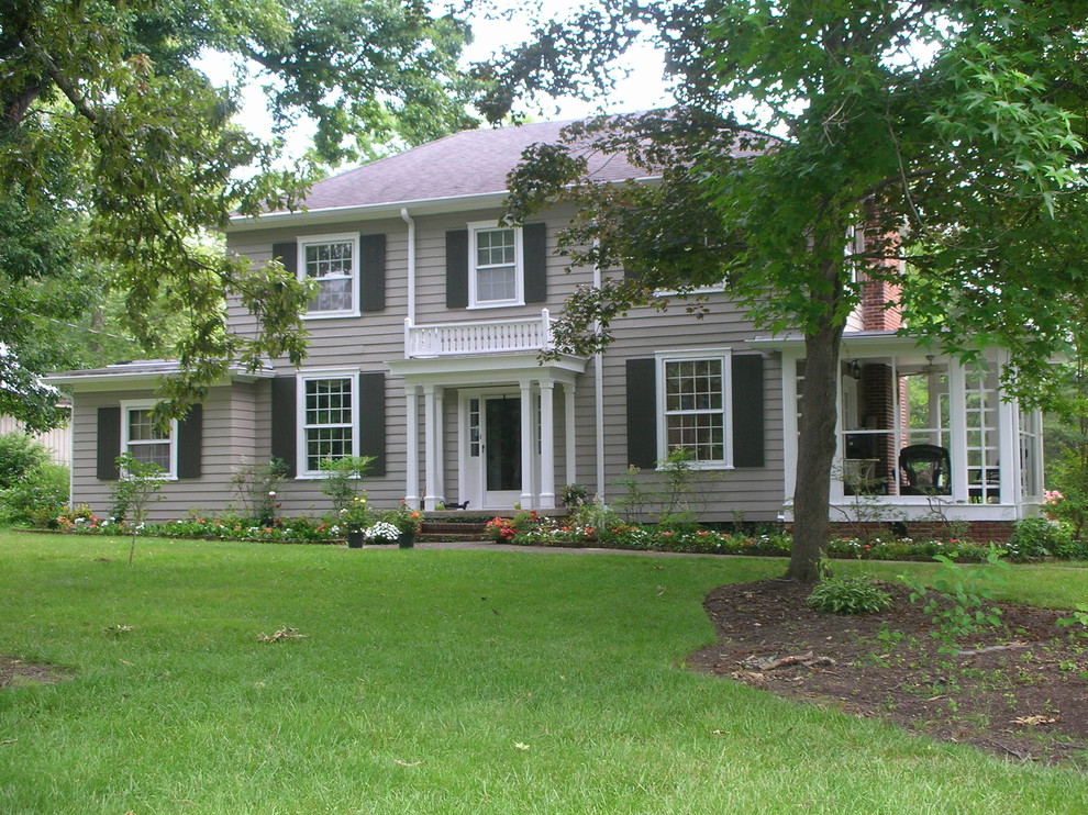 Cette photo montre une façade de maison grise chic de taille moyenne et à un étage avec un revêtement en vinyle et un toit à croupette.
