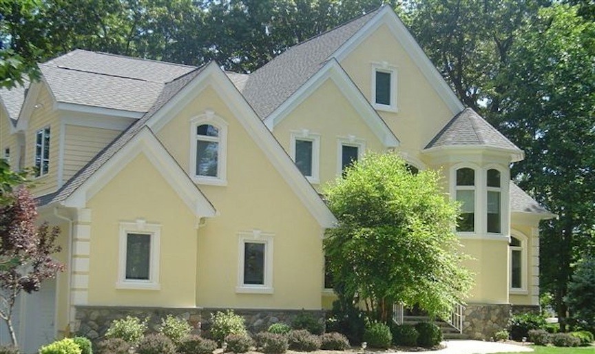 Esempio della facciata di una casa gialla country a due piani con rivestimento in stucco