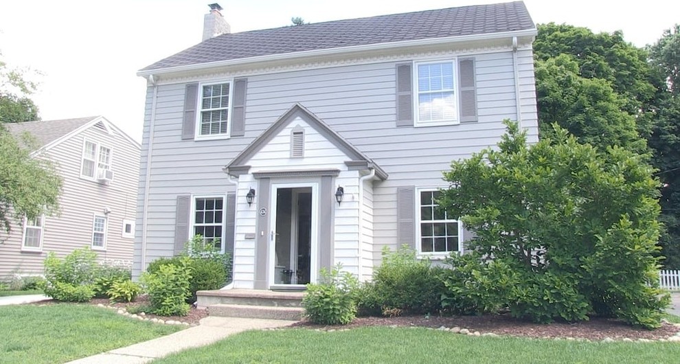 Exemple d'une façade de maison grise chic de taille moyenne et à un étage avec un toit à deux pans et un revêtement en vinyle.
