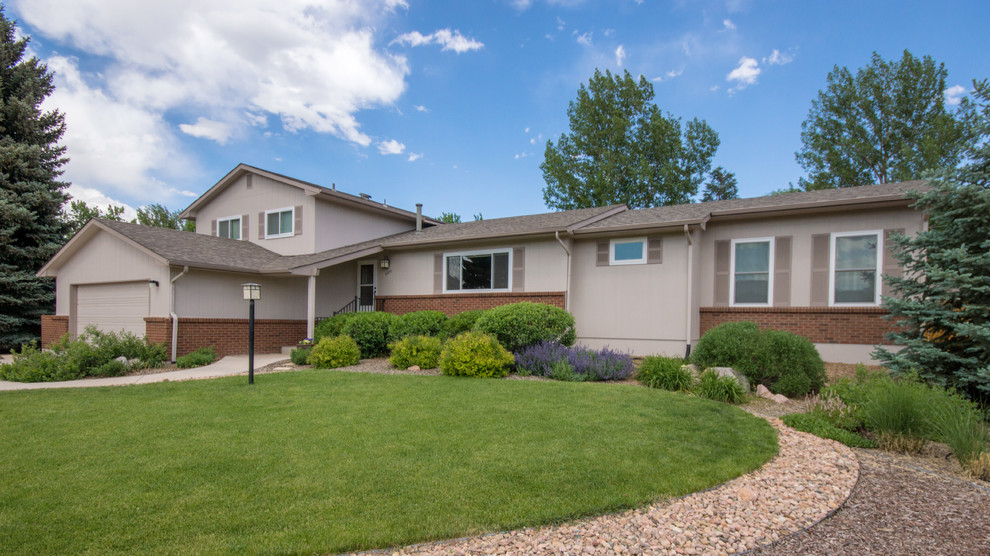 This is an example of a medium sized and beige classic split-level house exterior in Denver with concrete fibreboard cladding.