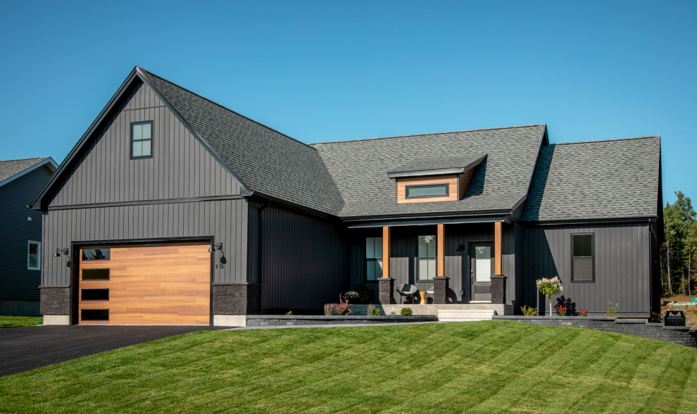 Ejemplo de fachada de casa negra escandinava grande de una planta con revestimiento de vinilo, tejado a dos aguas y tejado de teja de madera