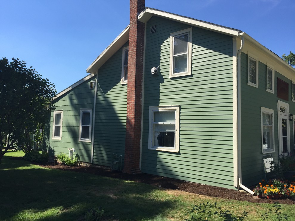 This is an example of a medium sized and green country two floor house exterior in Cleveland with vinyl cladding and a pitched roof.