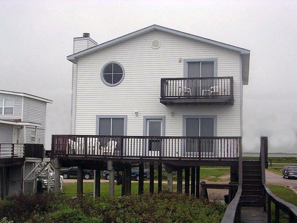 На фото: маленький, двухэтажный, белый частный загородный дом в морском стиле с облицовкой из ЦСП, двускатной крышей и крышей из гибкой черепицы для на участке и в саду с