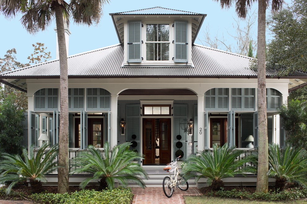 Ejemplo de fachada de casa azul tropical de tamaño medio de dos plantas con revestimientos combinados, tejado a cuatro aguas y tejado de metal