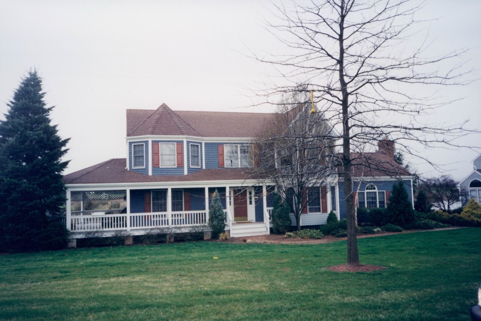 На фото: большой, двухэтажный, синий дом в классическом стиле с облицовкой из винила с