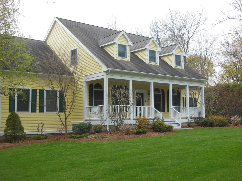 Cette image montre une façade de maison jaune traditionnelle de taille moyenne et à un étage avec un revêtement en vinyle, un toit à deux pans et un toit en tuile.