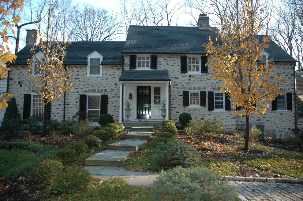 Cette photo montre une façade de maison beige chic en pierre de taille moyenne et à un étage avec un toit à deux pans et un toit en shingle.
