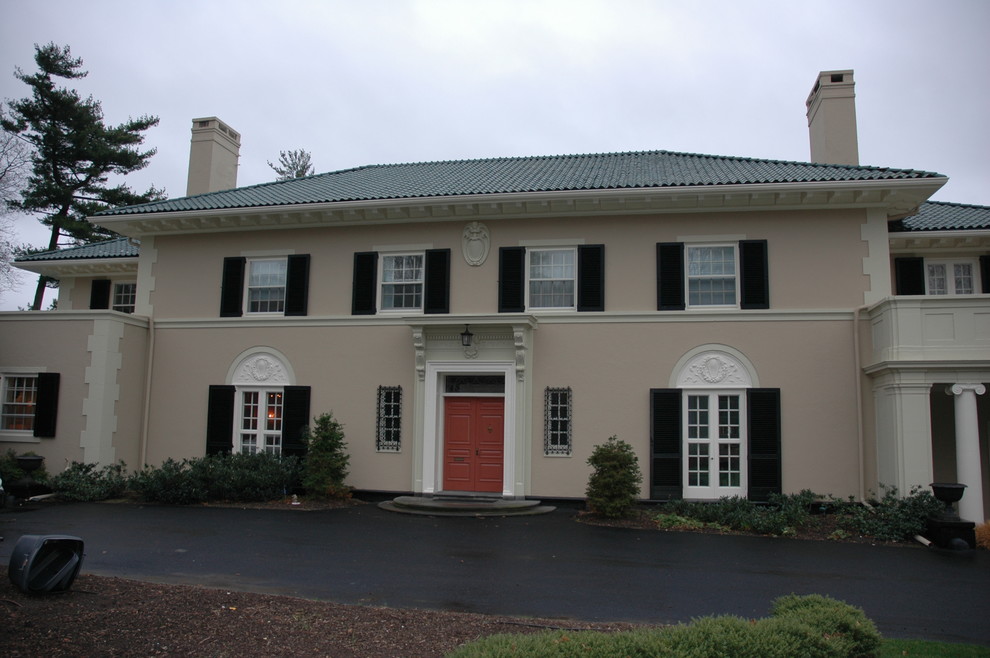 Immagine della facciata di una casa grande beige classica a due piani con tetto a padiglione e rivestimento in cemento