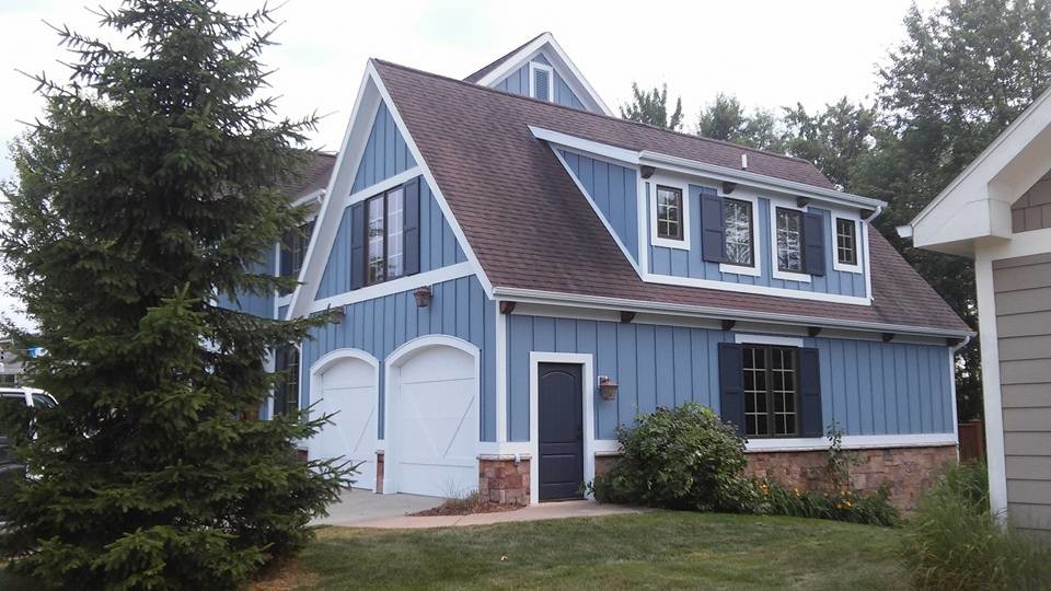 Immagine della facciata di una casa grande blu country a due piani con rivestimento in legno e tetto a padiglione