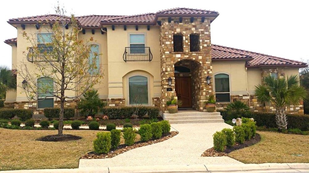 Photo of a large and beige mediterranean two floor render detached house in Austin with a hip roof and a tiled roof.